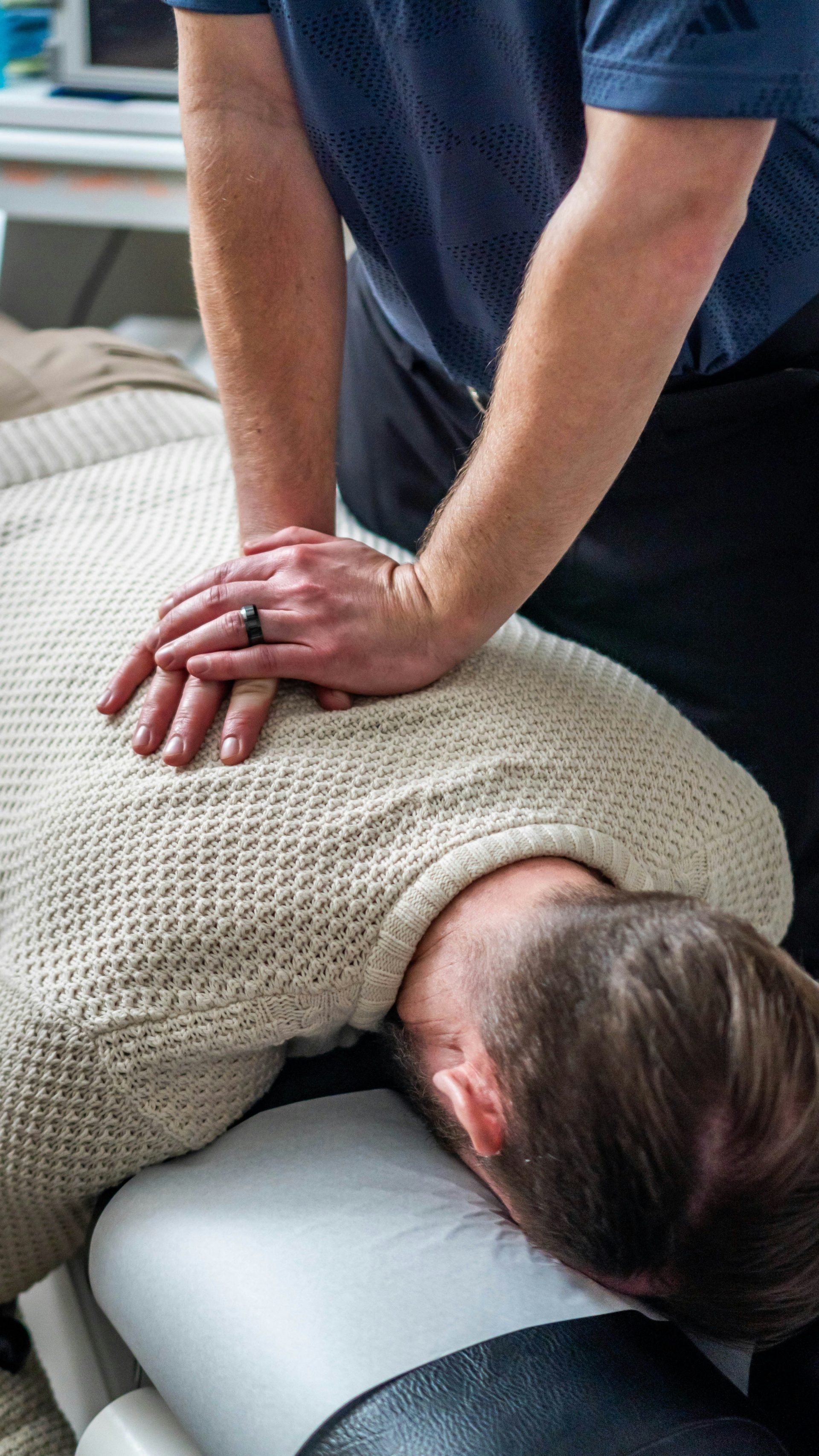 Chiropraktiker behandelt den oberen Rücken und Nacken eines Patienten.